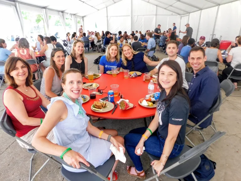 a group of guests around a table at a company picnic under a tent